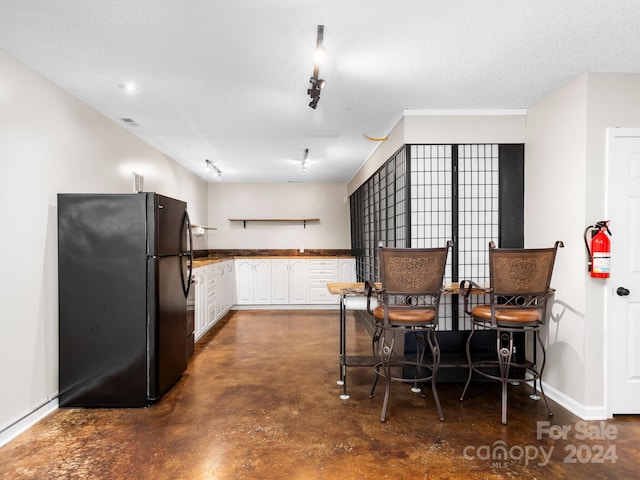 kitchen with white cabinets, black fridge, and a textured ceiling