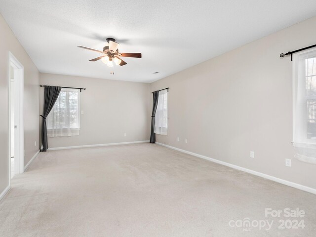 unfurnished room with ceiling fan, plenty of natural light, and light colored carpet