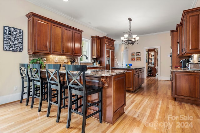 kitchen featuring light hardwood / wood-style floors, crown molding, backsplash, and dark stone counters