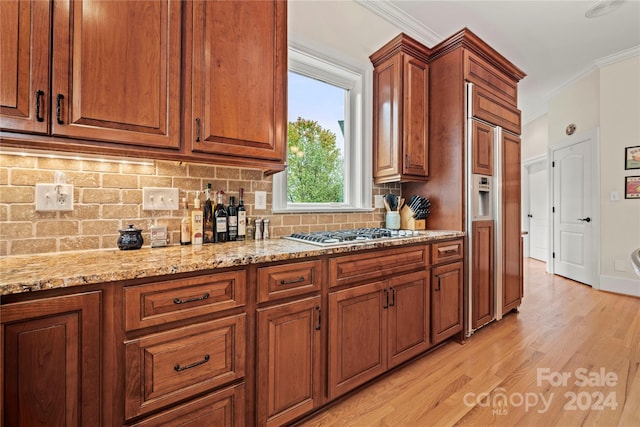 kitchen featuring backsplash, light hardwood / wood-style flooring, ornamental molding, light stone counters, and stainless steel gas cooktop