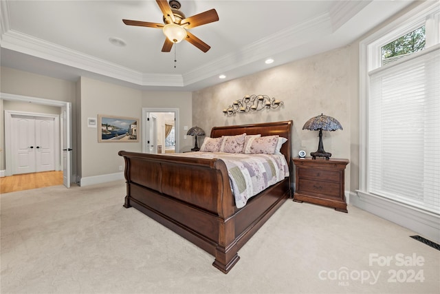 carpeted bedroom with ceiling fan, a raised ceiling, and crown molding