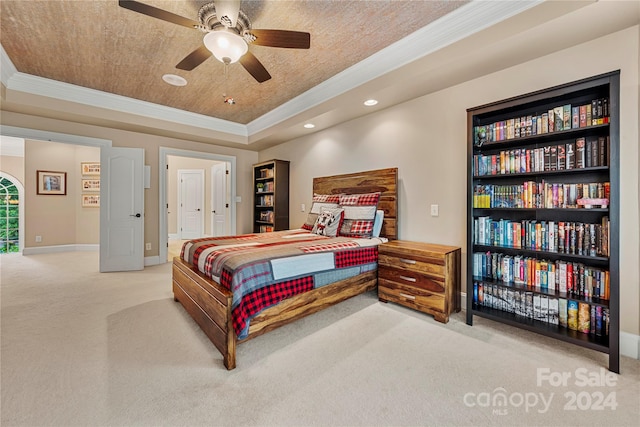 bedroom with carpet flooring, ceiling fan, ornamental molding, and a tray ceiling