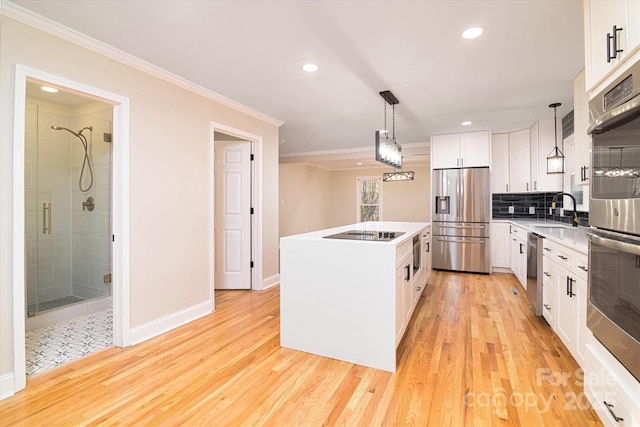 kitchen featuring light hardwood / wood-style floors, a center island, white cabinetry, hanging light fixtures, and stainless steel appliances