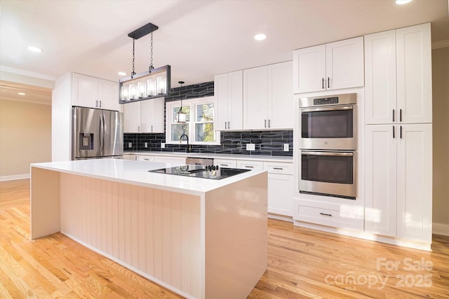 kitchen featuring pendant lighting, appliances with stainless steel finishes, a kitchen island, white cabinetry, and light hardwood / wood-style floors