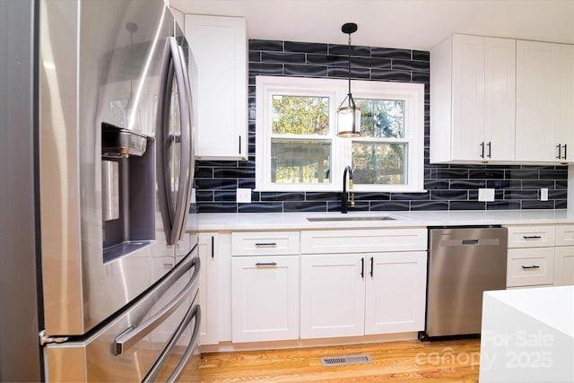 kitchen with white cabinetry, appliances with stainless steel finishes, backsplash, hanging light fixtures, and sink