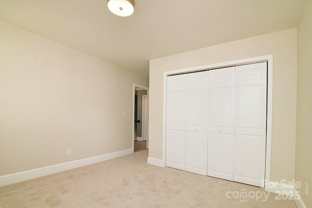 unfurnished bedroom with light colored carpet and a closet