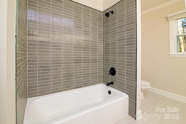 bathroom with toilet, tiled shower / bath combo, tile patterned flooring, and ornamental molding