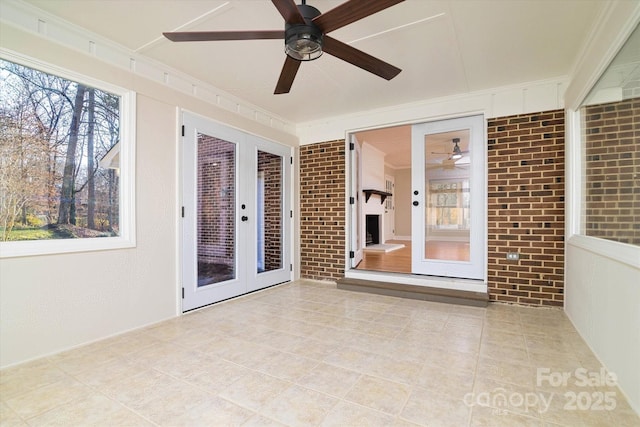 unfurnished sunroom featuring ceiling fan and french doors