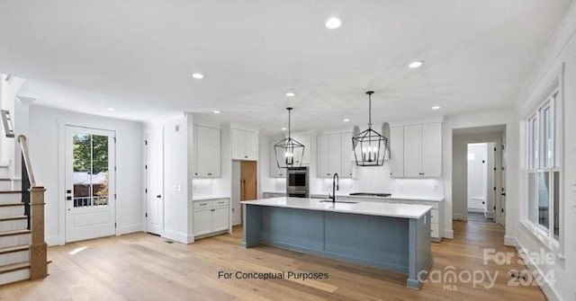 kitchen featuring light wood-type flooring, a kitchen island with sink, and hanging light fixtures