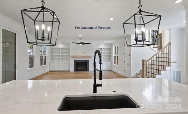 kitchen featuring built in shelves, light hardwood / wood-style floors, light stone counters, and hanging light fixtures