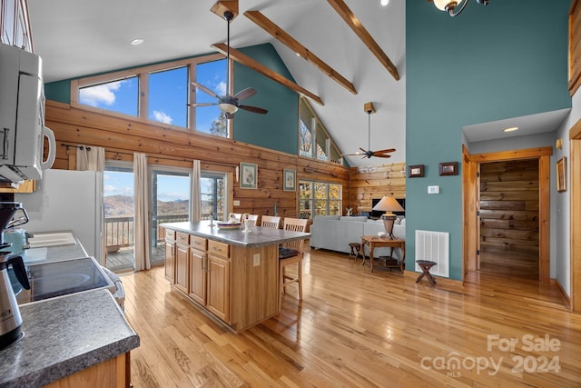 kitchen with a breakfast bar, white appliances, high vaulted ceiling, a kitchen island, and light hardwood / wood-style floors