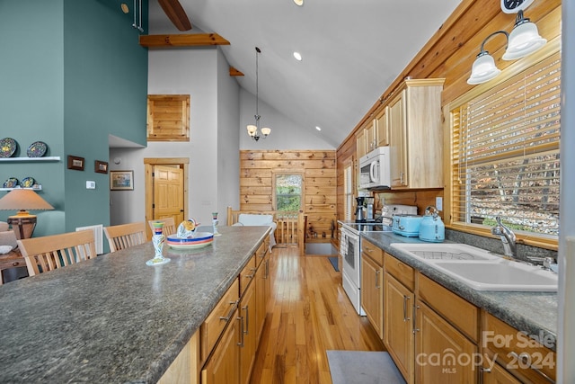 kitchen featuring white appliances, sink, pendant lighting, high vaulted ceiling, and wood walls