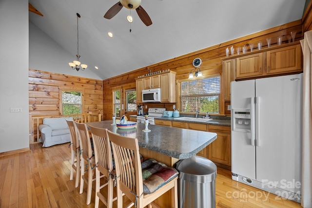 kitchen with sink, hanging light fixtures, light hardwood / wood-style flooring, white appliances, and a kitchen island