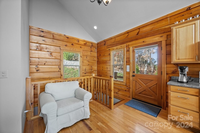 entrance foyer with light hardwood / wood-style floors, lofted ceiling, and wood walls