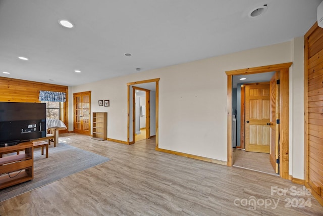 living room with wooden walls, a wall mounted air conditioner, and light wood-type flooring