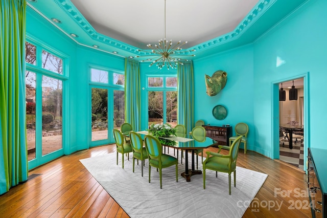 dining space with a tray ceiling, hardwood / wood-style floors, a chandelier, and french doors