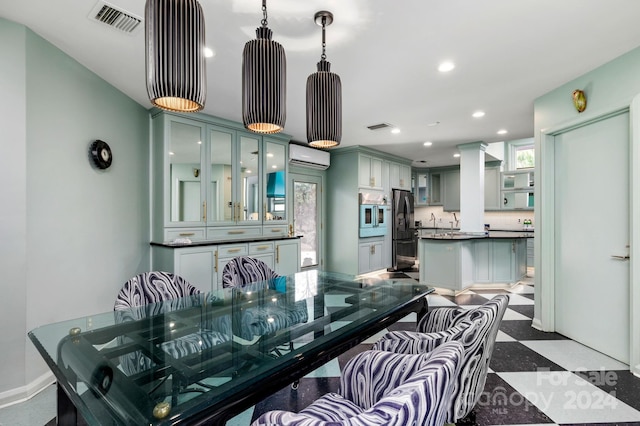 kitchen with a wall mounted air conditioner, hanging light fixtures, and appliances with stainless steel finishes