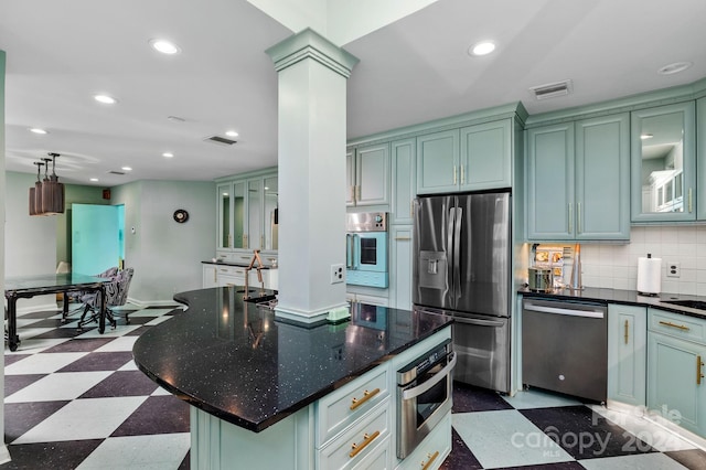 kitchen with a center island, green cabinets, decorative backsplash, dark stone countertops, and appliances with stainless steel finishes