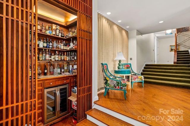 wine area featuring hardwood / wood-style flooring, beverage cooler, and bar area