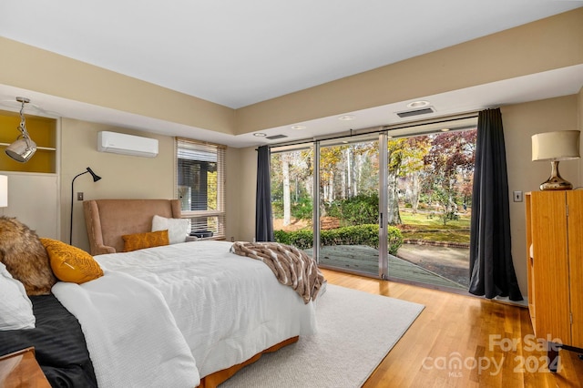 bedroom with access to exterior, a wall mounted air conditioner, and hardwood / wood-style flooring