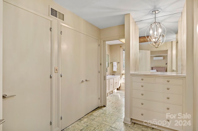 corridor with light parquet floors and a notable chandelier