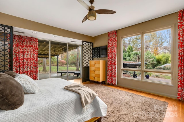 bedroom with access to outside, hardwood / wood-style flooring, multiple windows, and ceiling fan