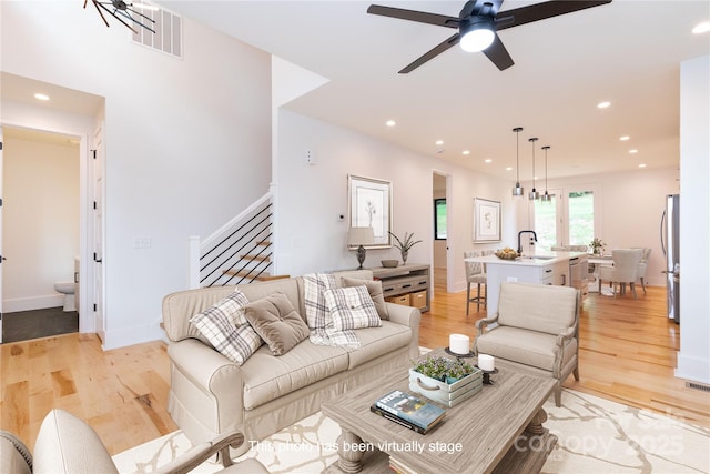 living room with sink, light hardwood / wood-style flooring, and ceiling fan