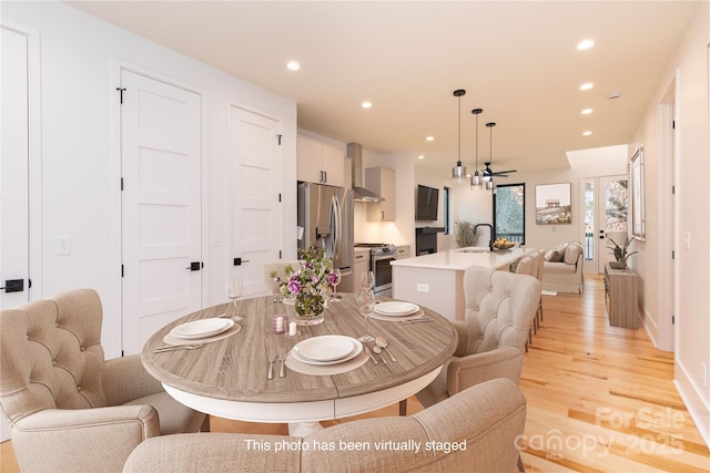 dining area featuring ceiling fan, sink, and light wood-type flooring