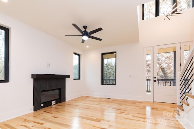 foyer with hardwood / wood-style flooring, a tile fireplace, and ceiling fan