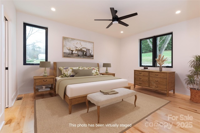 bedroom with ceiling fan, light hardwood / wood-style floors, and multiple windows