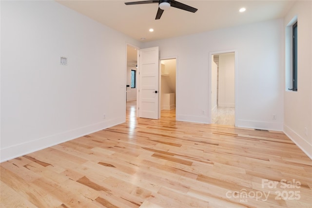 unfurnished bedroom with a walk in closet, ceiling fan, and light wood-type flooring