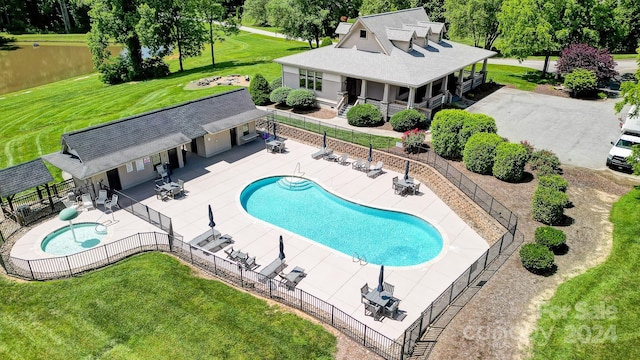 view of swimming pool featuring a yard, a water view, and a patio area