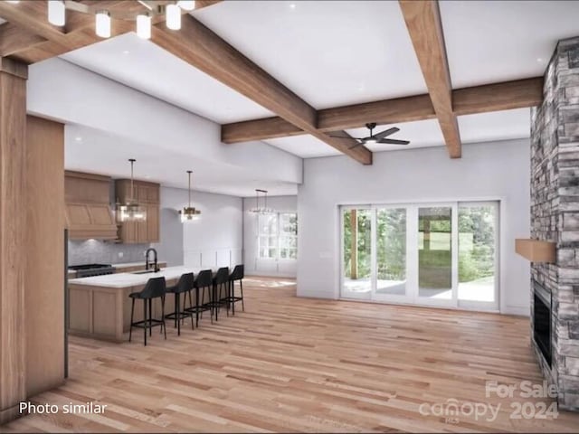 living room featuring ceiling fan with notable chandelier, light hardwood / wood-style flooring, a stone fireplace, and sink