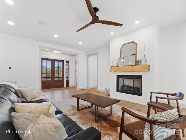 living room featuring french doors, a fireplace, recessed lighting, visible vents, and wood finished floors