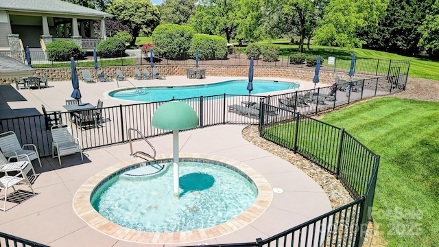 community pool with a patio area, fence, a hot tub, and a lawn