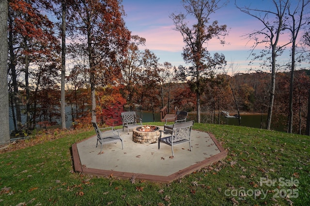 patio terrace at dusk featuring a yard and a fire pit