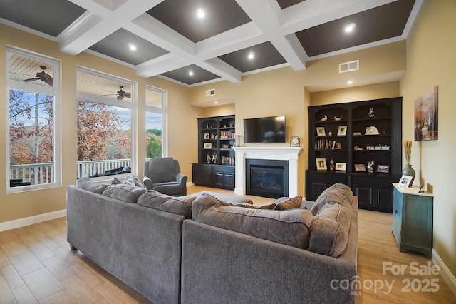 living room with light hardwood / wood-style floors, built in features, ceiling fan, and crown molding