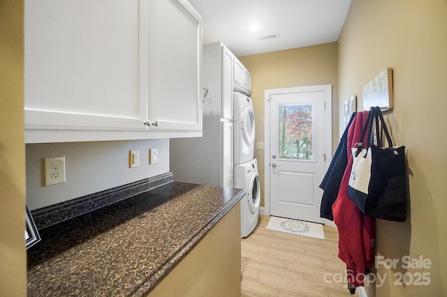 clothes washing area with light wood-type flooring and stacked washer / dryer