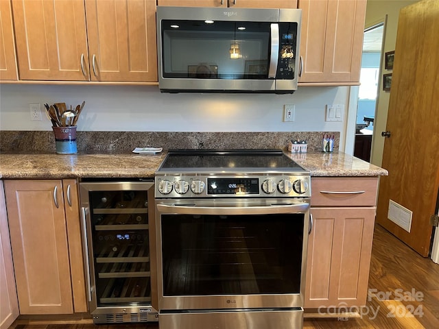 kitchen featuring appliances with stainless steel finishes, dark wood-type flooring, wine cooler, and dark stone counters