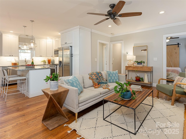 living room featuring crown molding, a barn door, and light hardwood / wood-style flooring