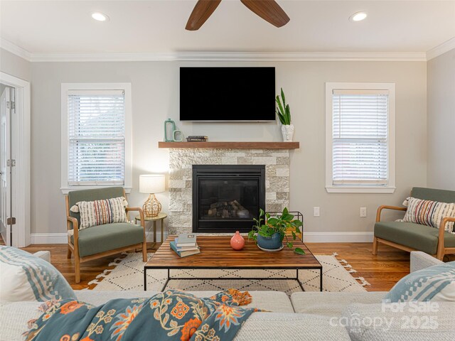 living room with ornamental molding, ceiling fan, and light wood-type flooring