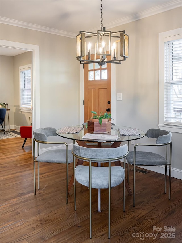 dining area featuring crown molding, dark wood-type flooring, and a chandelier