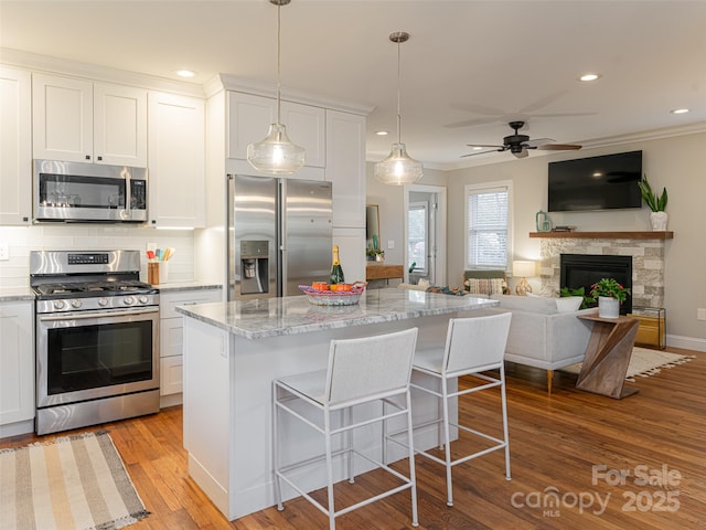 kitchen featuring white cabinetry, appliances with stainless steel finishes, a breakfast bar, and light stone counters