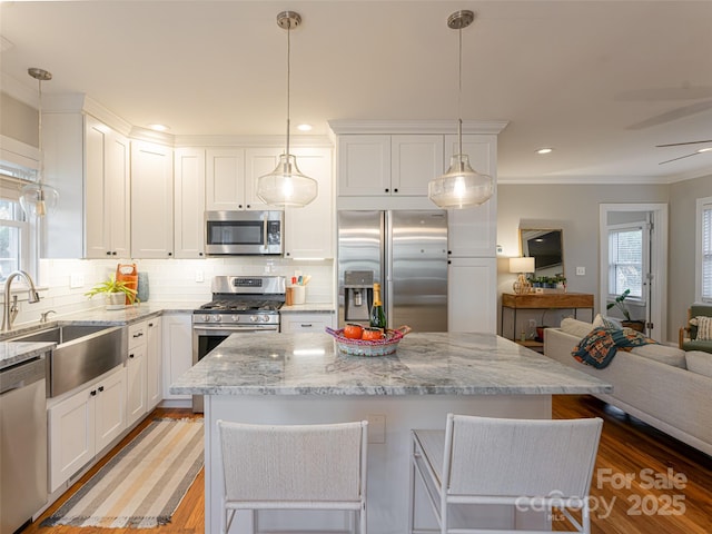 kitchen with sink, a breakfast bar area, stainless steel appliances, and white cabinets