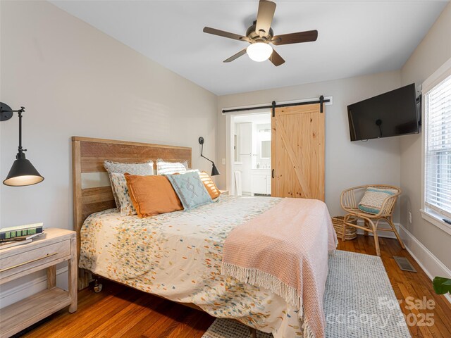 bedroom featuring hardwood / wood-style flooring, a barn door, and ceiling fan