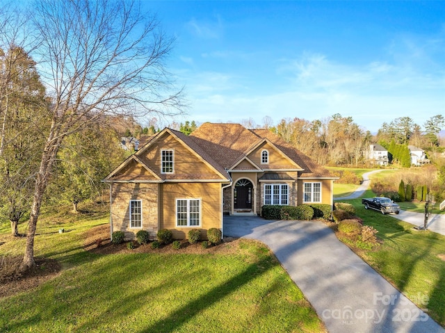 view of front facade with a front yard, stone siding, and driveway