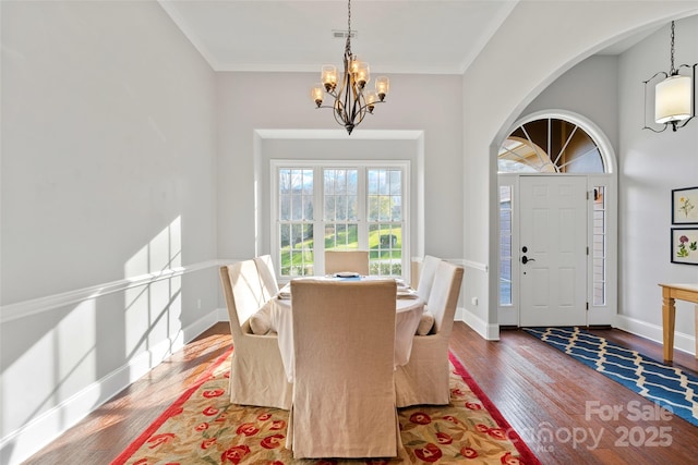 dining area featuring crown molding, a notable chandelier, baseboards, and wood finished floors