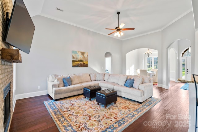 living area featuring ornamental molding, a brick fireplace, wood finished floors, and visible vents