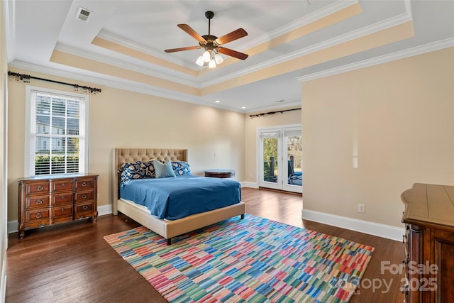 bedroom with access to exterior, multiple windows, a tray ceiling, and wood finished floors