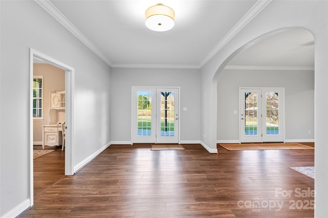 entrance foyer with dark wood-style floors, arched walkways, and baseboards